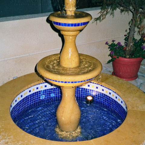 Stone garden fountain with a blue mosaic basin